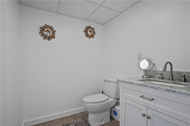 bathroom featuring vanity, toilet, a drop ceiling, and wood-type flooring