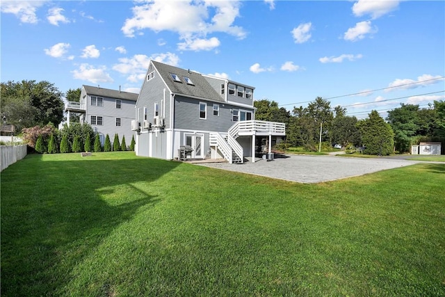 rear view of house featuring a lawn, a wooden deck, and a patio area