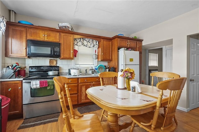 kitchen with light hardwood / wood-style floors, white fridge, electric stove, and backsplash