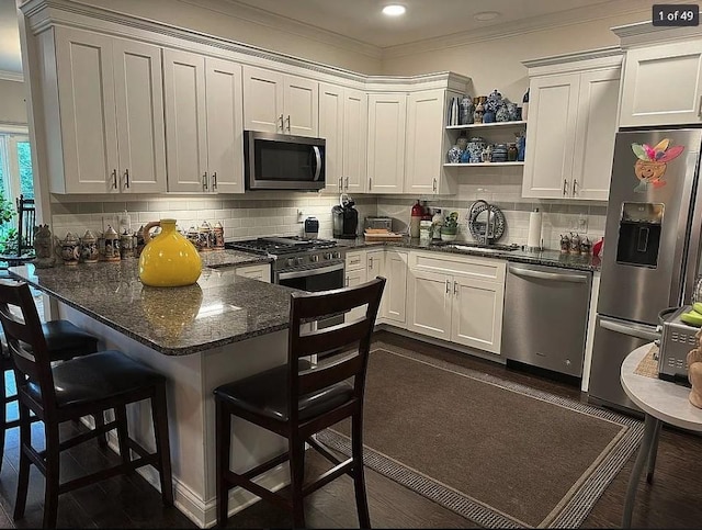 kitchen with dark stone countertops, a kitchen bar, white cabinetry, and stainless steel appliances