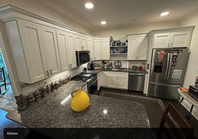 kitchen with dark stone counters, sink, decorative backsplash, appliances with stainless steel finishes, and white cabinetry