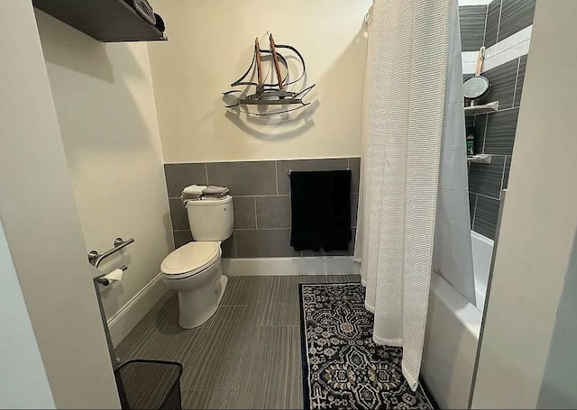 bathroom featuring toilet, shower / bathtub combination with curtain, and tile walls