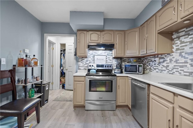 kitchen featuring decorative backsplash, light brown cabinetry, light hardwood / wood-style flooring, and appliances with stainless steel finishes