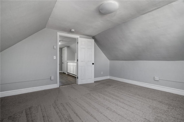 bonus room featuring lofted ceiling and dark colored carpet