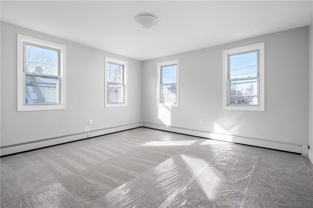 spare room featuring a baseboard heating unit and light colored carpet