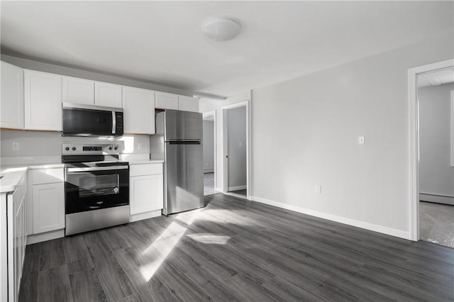 kitchen with appliances with stainless steel finishes, pendant lighting, dark wood-type flooring, a wealth of natural light, and white cabinets