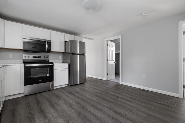 kitchen with stainless steel appliances, white cabinetry, and dark hardwood / wood-style flooring