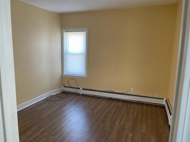 spare room featuring dark hardwood / wood-style flooring and a baseboard radiator