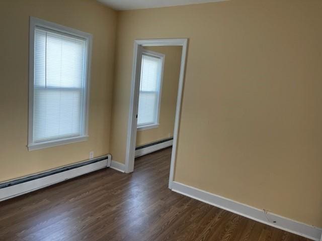 empty room with dark wood-type flooring and a baseboard radiator