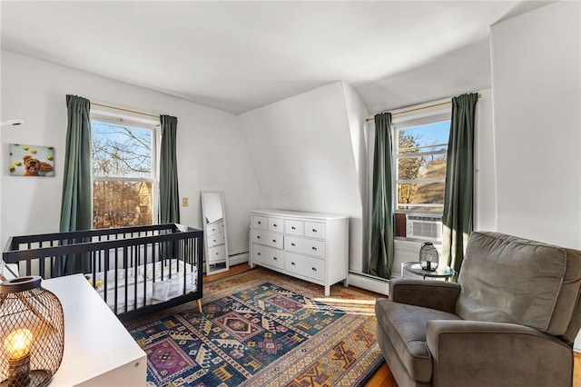 bedroom with cooling unit, a crib, and a baseboard heating unit