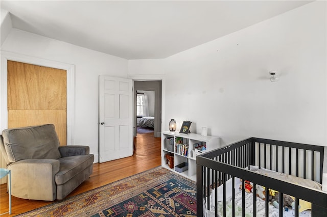 bedroom with a nursery area and wood-type flooring