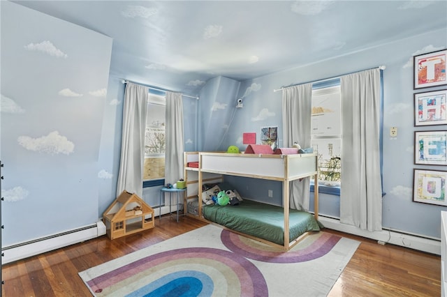 bedroom with hardwood / wood-style floors and a baseboard heating unit