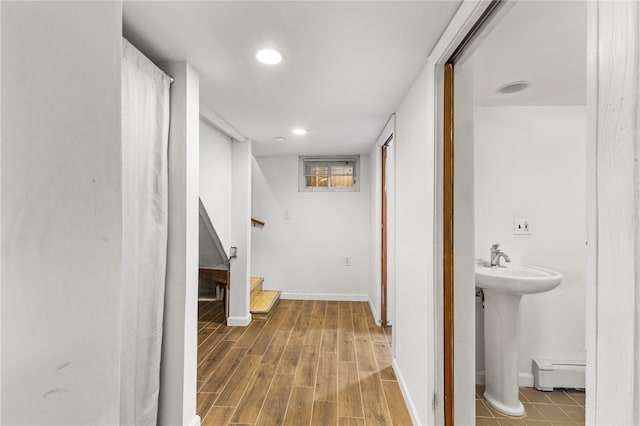 bathroom with hardwood / wood-style flooring, a baseboard heating unit, and sink