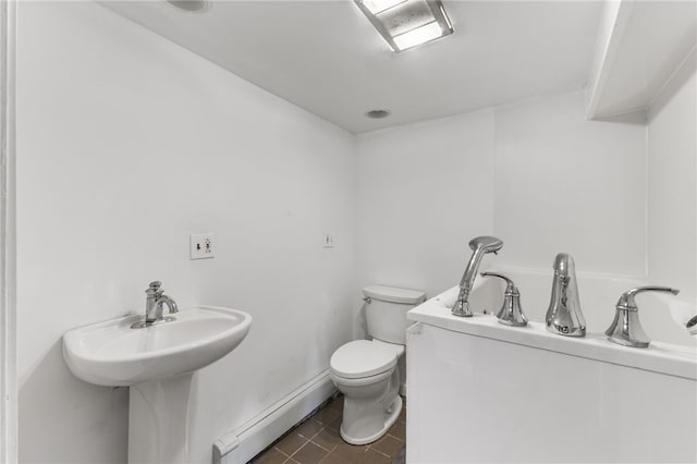 bathroom featuring tile patterned flooring, a washtub, toilet, and baseboard heating