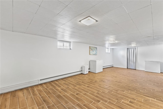 basement featuring hardwood / wood-style floors, a healthy amount of sunlight, and a baseboard radiator