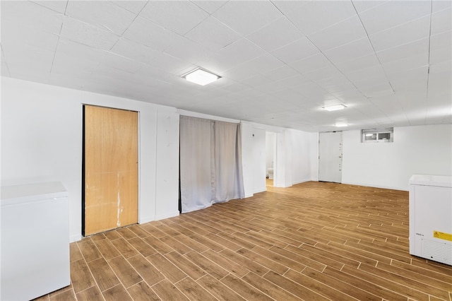 basement featuring refrigerator and hardwood / wood-style flooring