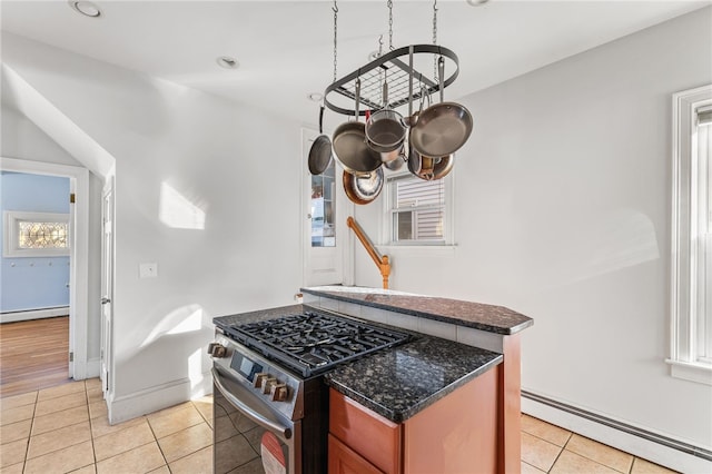 kitchen featuring light tile patterned floors, high end stove, a baseboard radiator, and plenty of natural light