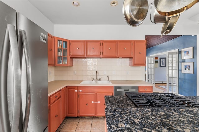 kitchen featuring backsplash, sink, light tile patterned floors, baseboard heating, and appliances with stainless steel finishes