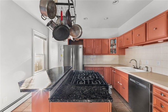 kitchen with sink, a kitchen island, a baseboard heating unit, light tile patterned floors, and appliances with stainless steel finishes