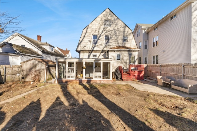 rear view of house featuring a patio area, a sunroom, and a shed