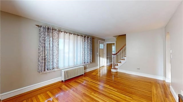 spare room featuring radiator heating unit and hardwood / wood-style flooring