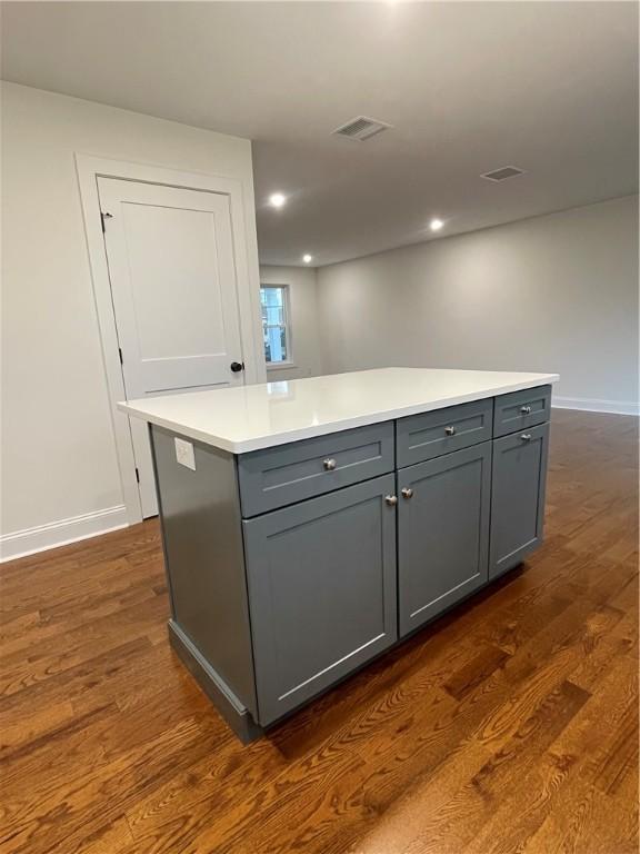 kitchen with gray cabinetry, a center island, and dark wood-type flooring