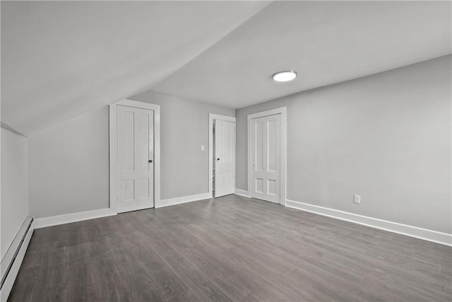 additional living space with dark hardwood / wood-style flooring, lofted ceiling, and a baseboard heating unit