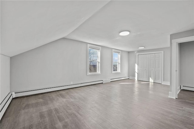 additional living space featuring hardwood / wood-style flooring, vaulted ceiling, and a baseboard radiator