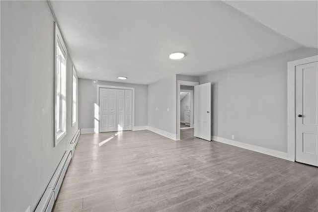 interior space featuring vaulted ceiling, light hardwood / wood-style flooring, and a baseboard heating unit