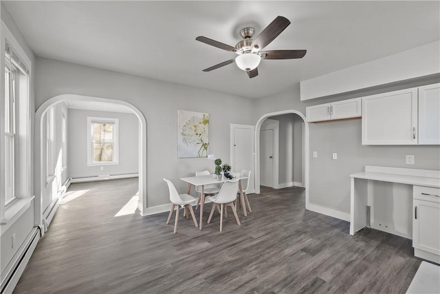 dining area featuring a healthy amount of sunlight, dark hardwood / wood-style floors, ceiling fan, and a baseboard heating unit