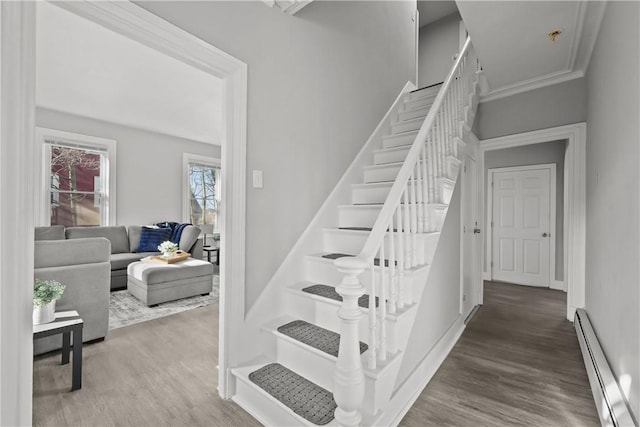 stairs with crown molding, hardwood / wood-style floors, and a baseboard radiator