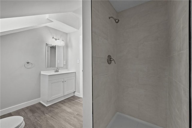 bathroom featuring a tile shower, vanity, hardwood / wood-style flooring, and toilet