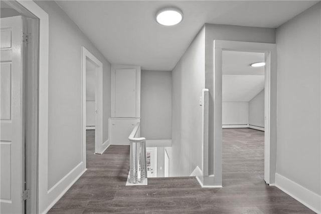 hallway with a baseboard heating unit and dark wood-type flooring