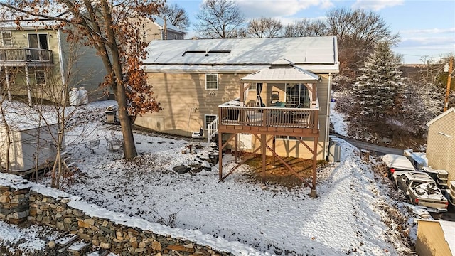 snow covered back of property featuring a deck