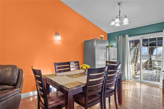 dining space featuring vaulted ceiling, light hardwood / wood-style flooring, and an inviting chandelier