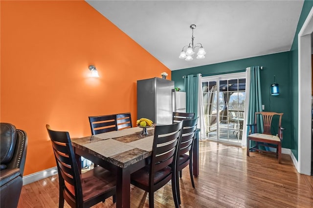 dining room with lofted ceiling, wood-type flooring, and an inviting chandelier