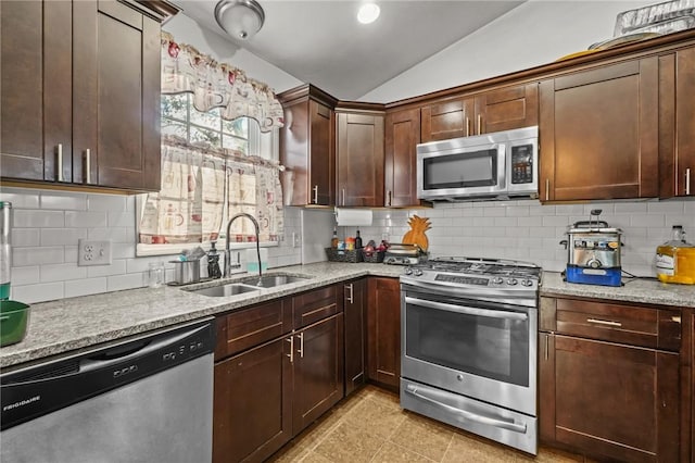 kitchen with decorative backsplash, light stone counters, stainless steel appliances, sink, and lofted ceiling