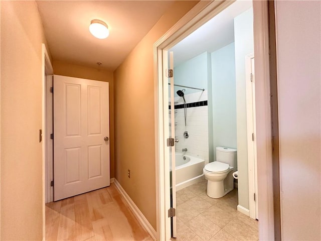 bathroom featuring tiled shower / bath combo and toilet