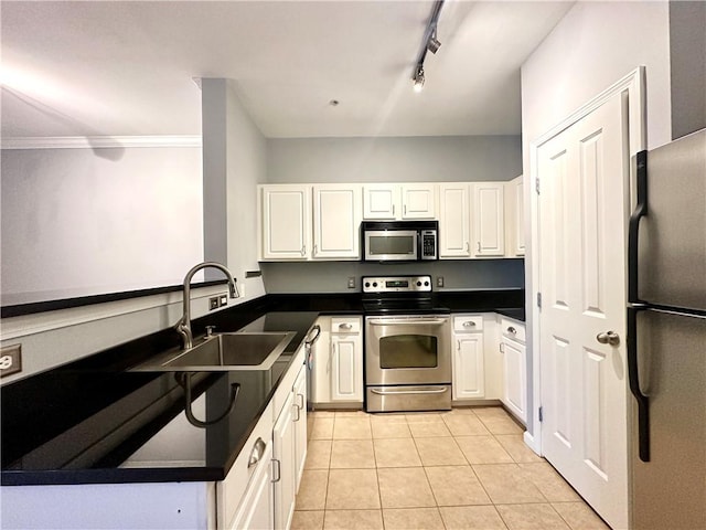 kitchen featuring rail lighting, stainless steel appliances, sink, white cabinetry, and light tile patterned flooring