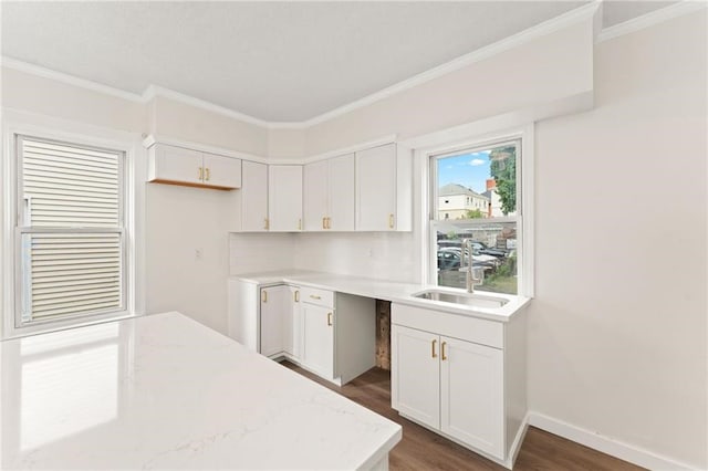 kitchen with light stone countertops, sink, and white cabinets