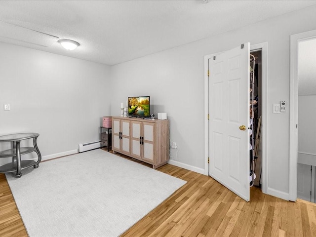 misc room with hardwood / wood-style flooring, baseboard heating, and a textured ceiling