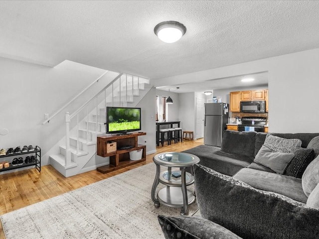 living room with a textured ceiling and light hardwood / wood-style flooring