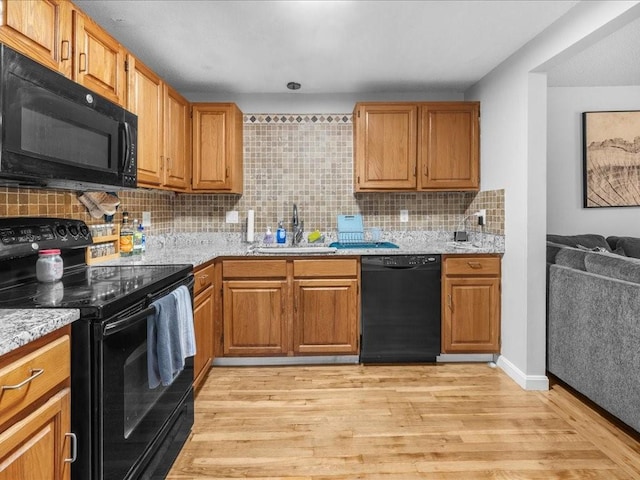 kitchen with backsplash, sink, black appliances, and light wood-type flooring