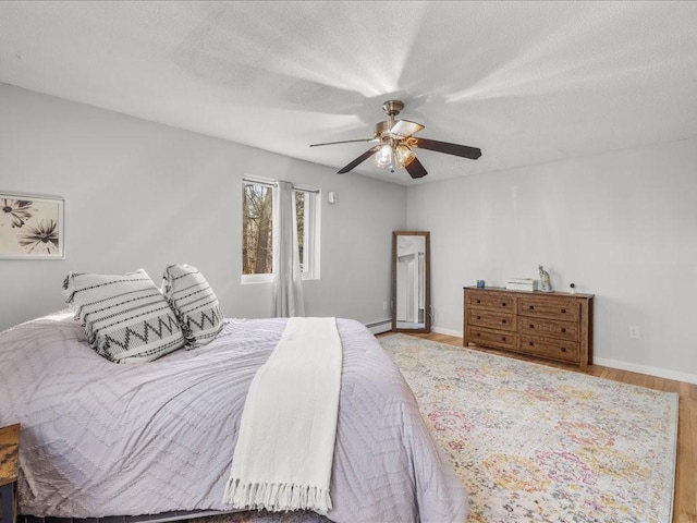 bedroom with ceiling fan, wood-type flooring, a textured ceiling, and a baseboard radiator