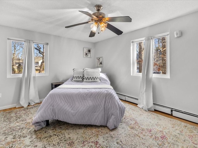 bedroom featuring multiple windows, ceiling fan, a baseboard radiator, and a textured ceiling