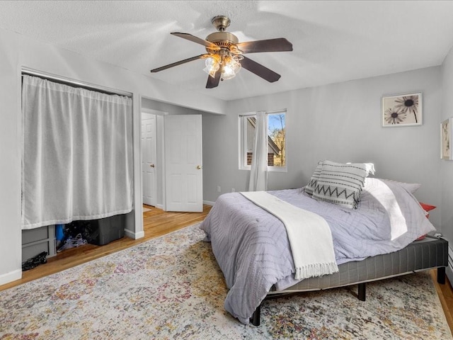 bedroom featuring ceiling fan, light wood-type flooring, and a textured ceiling