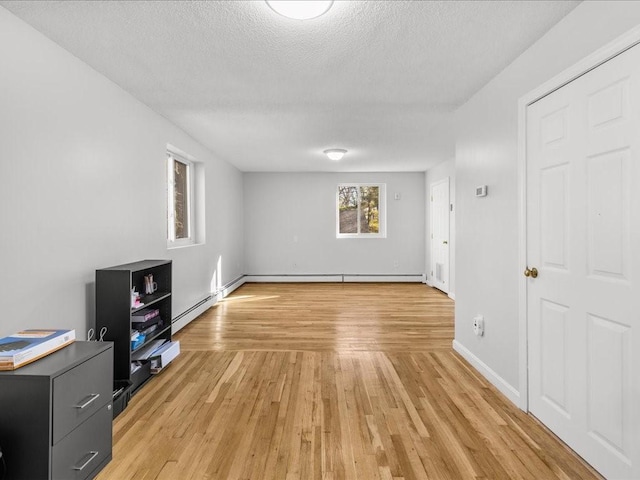 unfurnished living room featuring baseboard heating, a textured ceiling, and light wood-type flooring