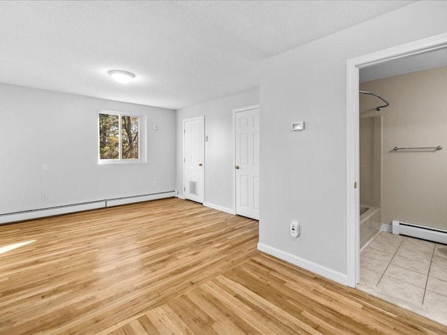 unfurnished bedroom featuring a baseboard radiator, ensuite bath, and light hardwood / wood-style floors