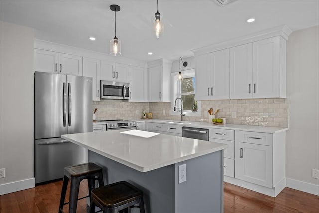 kitchen featuring dark hardwood / wood-style flooring, a center island, stainless steel appliances, and white cabinetry