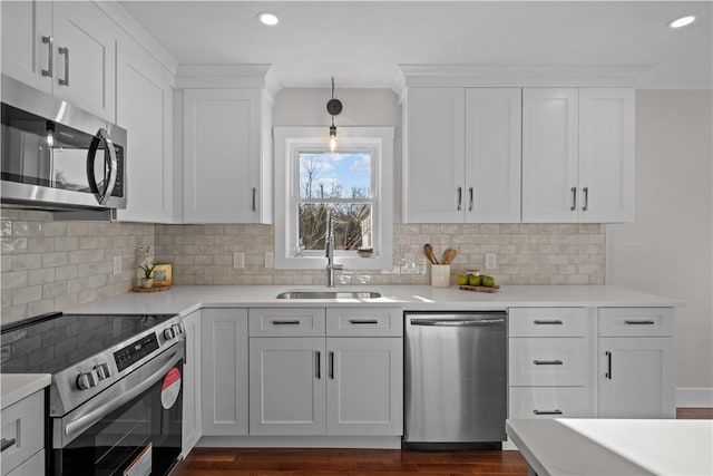 kitchen with backsplash, stainless steel appliances, sink, pendant lighting, and white cabinetry